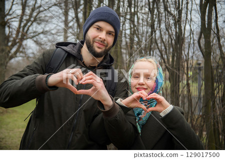 Young couple are making heart with their hands in park 129017500