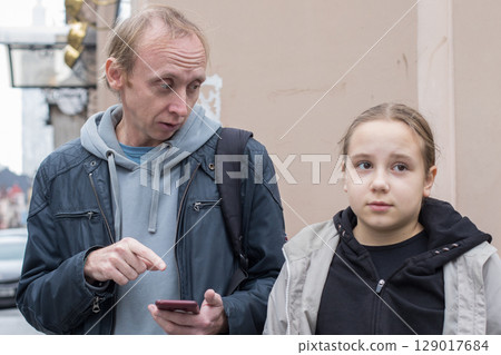 Unhappy daughter and her father using smartphone app outdoors 129017684