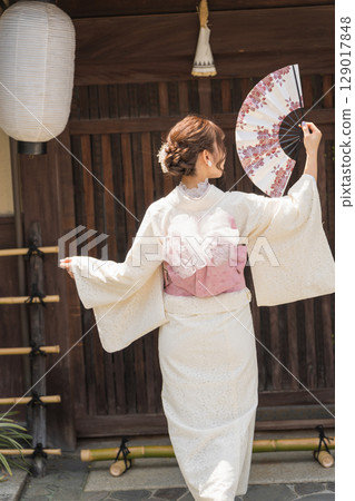A woman in a white kimono holding a folding fan. Gion, Kyoto, Japan A woman in a white kimono holding a folding fan. Gion, Kyoto, Japan 129017848