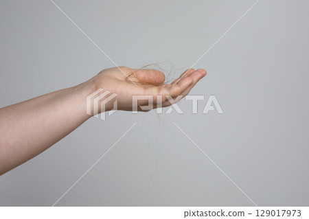 Female hand holding hair fall or loss on white background. Hair problem 129017973