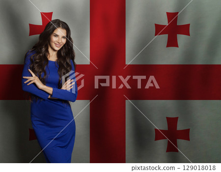 Cheerful young woman in blue dress smiling against Georgian flag background Cheerful young woman in blue dress smiling against Georgian flag background 129018018