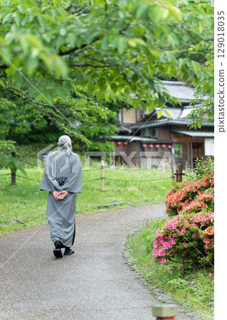 An elderly man in a kimono looking at an old house. Kyoto, Japan 129018035