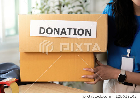 Volunteer carrying donation box, promoting community support Volunteer carrying donation box, promoting community support 129018102