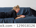 Happy girl using mobile phone on sofa at home 129018126