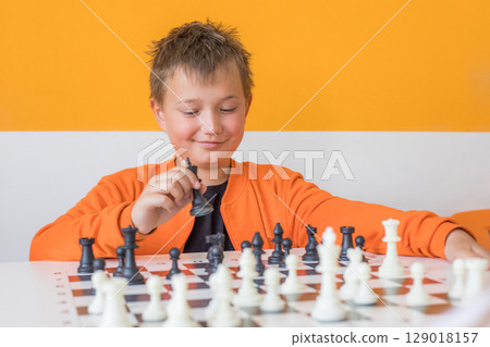 Smart school boy student playing chess in the classroom. Child with chess indoor 129018157