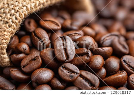 Roasted coffee beans spilling from burlap sack, close up 129018317