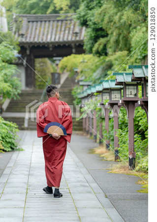 一名身穿紅色和服的年輕男子走在日本京都的神社參拜道上 129018850