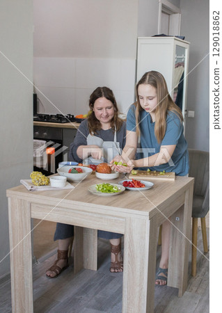 Family together. Mother teaching daughter how to prepare vegetables 129018862