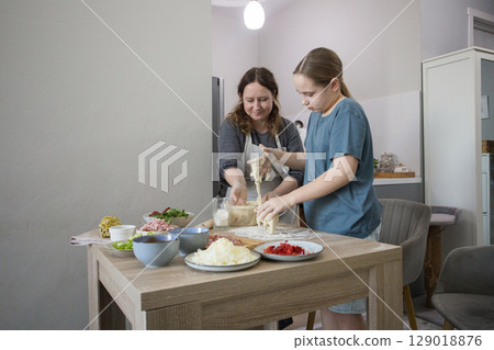 Hobby. Child girl daughter and mother preparing dough for pizza and smiling  129018876