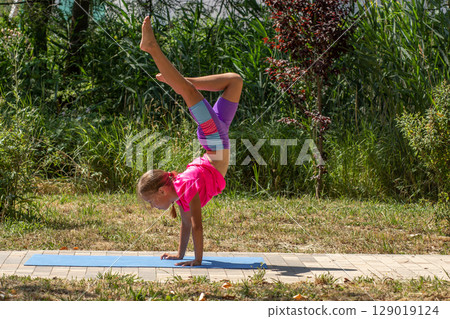 Child balancing in a one-legged handstand pose Child balancing in a one-legged handstand pose 129019124