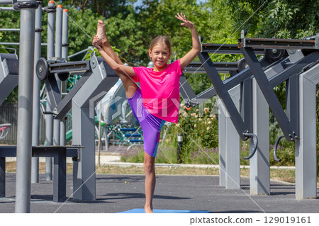 Child standing on one leg holding the other leg up in a stretch Child standing on one leg holding the other leg up in a stretch 129019161