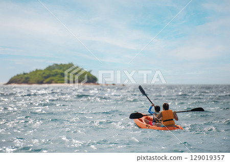 Mother and child kayaking adventure across the sea to a secluded island. Mother and child kayaking adventure across the sea to a secluded island. 129019357