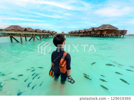 A diver in full gear stands amidst a school of fish in the clear blue sea on a bright sunny day. A diver in full gear stands amidst a school of fish in the clear blue sea on a bright sunny day. 129019360