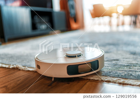 White robotic vacuum cleaner on wooden floor White robotic vacuum cleaner on wooden floor 129019556