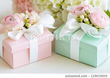 Pastel gift boxes in mint and pink tones adorned with delicate flowers and soft white ribbons creating an elegant display 129019850
