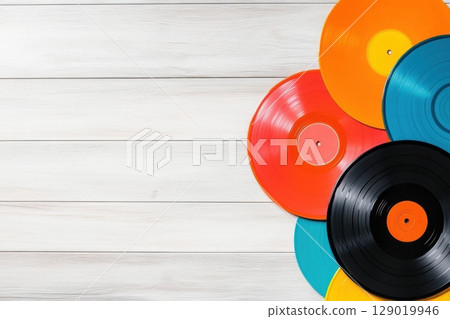 Colorful vintage vinyl records arranged in a flat lay on a rustic wooden floor for a nostalgic music experience 129019946