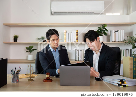 Legal Professionals. Lawyer and client reviewing documents in modern workspace. Legal Professionals. Lawyer and client reviewing documents in modern workspace. 129019976