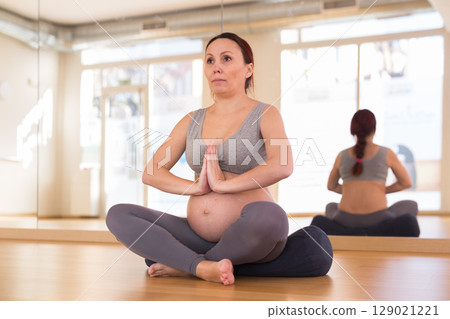 Pregnant woman is engaged in yoga. Easy pose or sukhasana Pregnant woman is engaged in yoga. Easy pose or sukhasana 129021221