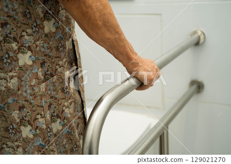 Asian elderly woman patient use toilet support rail in bathroom. Asian elderly woman patient use toilet support rail in bathroom. 129021270