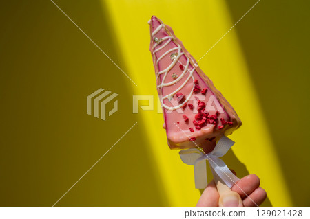 Female hand holding trendy sweet dessert cheesecake on colorful vibrant yellow background. Takeout takeaway present idea. Copy space for advertisement homemade cake bakery treat trend Female hand holding trendy sweet dessert cheesecake on colorful vibrant yellow background. Takeout takeaway present idea. Copy space for advertisement homemade cake bakery treat trend 129021428