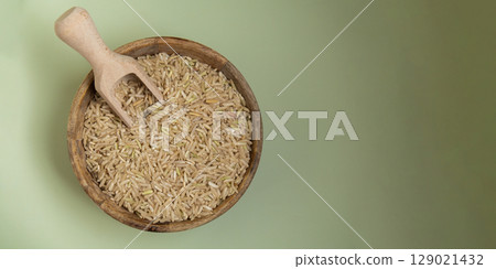 Brown rice in green background copy space. Whole spelt grain species. High protein fiber-rich vegan plant based food ingredient. Gluten free superfood healthy nutritional dietary alternative 129021432