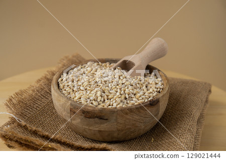 Pearl barley in neutral beige background. Whole spelt grain species. High protein fiber-rich vegan plant based food ingredient. Gluten free superfood healthy nutritional dietary alternative Pearl barley in neutral beige background. Whole spelt grain species. High protein fiber-rich vegan plant based food ingredient. Gluten free superfood healthy nutritional dietary alternative 129021444