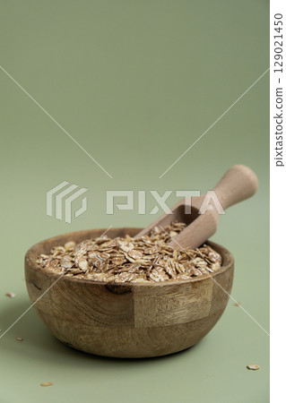 Raw oatmeal porridge in green background copy space. Whole spelt grain species. High protein fiber-rich vegan plant based food ingredient. Gluten free superfood healthy nutritional dietary alternative Raw oatmeal porridge in green background copy space. Whole spelt grain species. High protein fiber-rich vegan plant based food ingredient. Gluten free superfood healthy nutritional dietary alternative 129021450