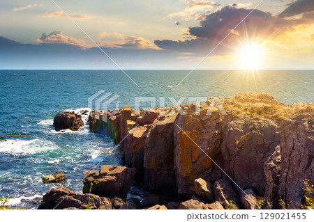 landscape with sea and coast with rock at sunset. vacation season with beautiful seascape in summer. travel background with water splash on stone in evening light landscape with sea and coast with rock at sunset. vacation season with beautiful seascape in summer. travel background with water splash on stone in evening light 129021455