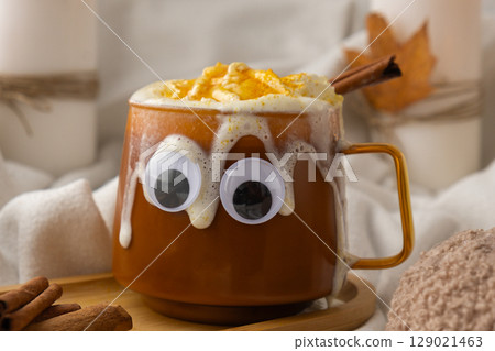 Seasonal drink cacao coffee with whipped cream and cinnamon sticks Halloween funny face on cup Hello Fall Halloween concept. Celebrating autumn holidays at cozy home on the windowsill atmosphere Seasonal drink cacao coffee with whipped cream and cinnamon sticks Halloween funny face on cup Hello Fall Halloween concept. Celebrating autumn holidays at cozy home on the windowsill atmosphere 129021463