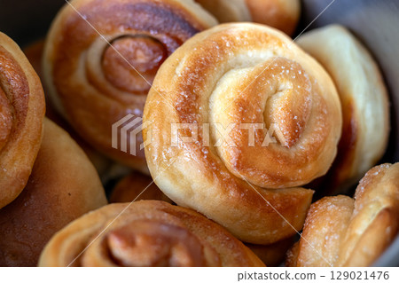 Freshly baked appetizing cinnamon and sugar rolls in close-up 129021476