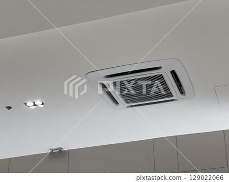 Modern white cassette air conditioner system on ceiling providing cool comfort. An indoor unit for ventilation, air conditioning, and climate control technology at home or office Modern white cassette air conditioner system on ceiling providing cool comfort. An indoor unit for ventilation, air conditioning, and climate control technology at home or office 129022066