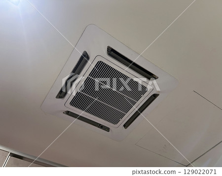 Modern cassette air conditioner mounted on white ceiling for interior climate control. ventilation system provides cool comfort and fresh air for comfortable home or office Modern cassette air conditioner mounted on white ceiling for interior climate control. ventilation system provides cool comfort and fresh air for comfortable home or office 129022071