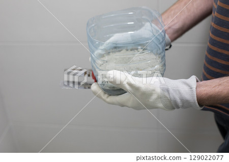 Cement glue for bathroom renovation work in male hands Cement glue for bathroom renovation work in male hands 129022077