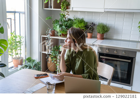 Exhausted pensive woman calculating utility bills working on laptop. Financial pressure, cost saving 129022181