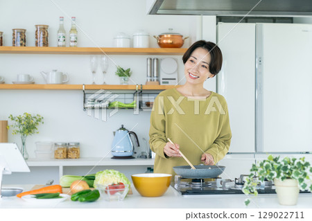 Middle-aged housewife cooking in the kitchen 129022711