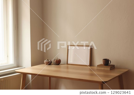 Autumn interior still life. Cup of tea, coffee, old books and pumpkins on wooden table at window. Horizontal picture frame, poster mockup. Home office. Minimal Scandi interior. Thanksgiving home decor Autumn interior still life. Cup of tea, coffee, old books and pumpkins on wooden table at window. Horizontal picture frame, poster mockup. Home office. Minimal Scandi interior. Thanksgiving home decor 129023641