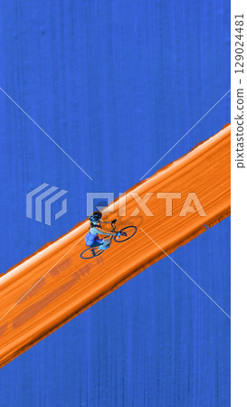 Digital artwork. Female cyclist riding along bright orange painted road on deep blue background 129024481