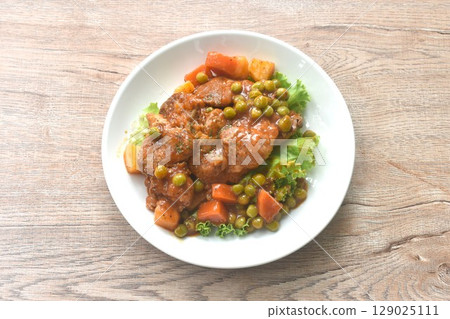 braised pork steak in gravy sauce stew with vegetable topping fresh lettuce on plate braised pork steak in gravy sauce stew with vegetable topping fresh lettuce on plate 129025111