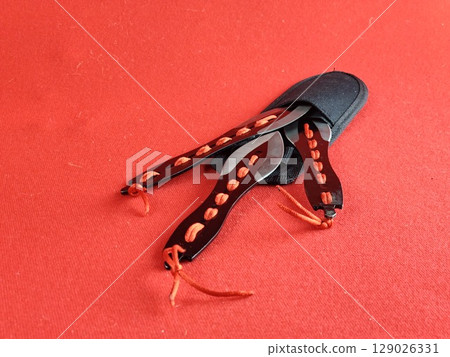 A set of several throwing knives in a case for combat training and sport throwing on red background. A set of several throwing knives in a case for combat training and sport throwing on red background. 129026331