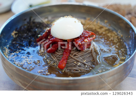 Close-up of Korean Buckwheat Noodles with Braised Pollack in Metal Bowl 129026343