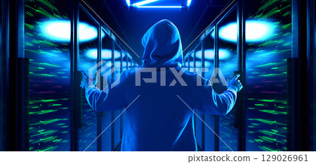 Hooded man standing with arms raised in server corridor 129026961