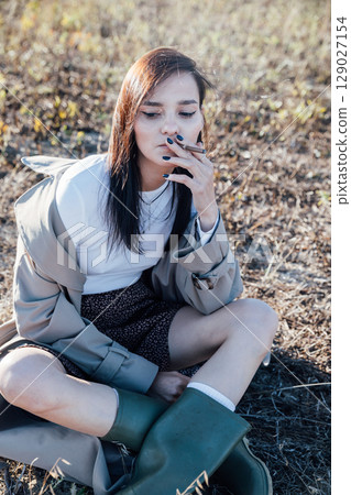 woman sitting on the ground and smoking 129027154