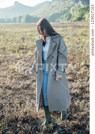 Beautiful woman in a coat walking in an autumn field 129027163