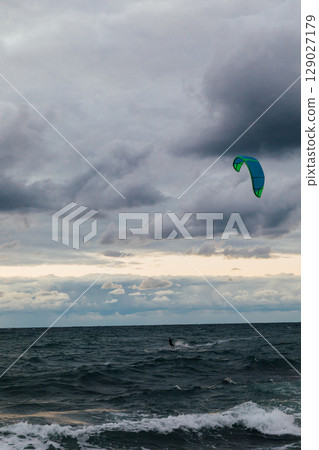 Kite surfing athlete riding waves in storm Kite surfing athlete riding waves in storm 129027179