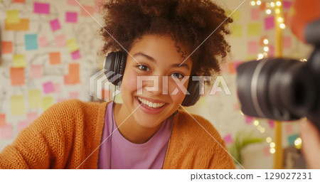 Blogger young woman with curly hair smiling in cozy room, concept of joyful lifestyle Blogger young woman with curly hair smiling in cozy room, concept of joyful lifestyle 129027231