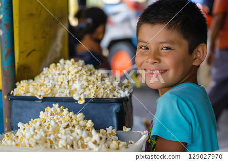 Smiling Latin boy sells popcorn on the street in Honduras, embodying childhood entrepreneurship in a developing country 129027970