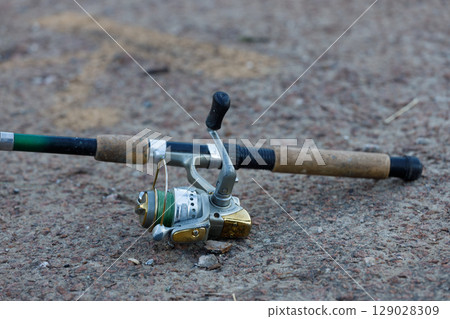 A Fishing Rod and Reel on the Ground: Capturing the Essence of Angling Adventures and Outdoor Experiences for Fishing Enthusiasts and Nature Lovers Alike A Fishing Rod and Reel on the Ground: Capturing the Essence of Angling Adventures and Outdoor Experiences for Fishing Enthusiasts and Nature Lovers Alike 129028309