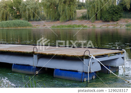 Serene Floating Dock on Crystal Clear Waters Surrounded by Lush Greenery with Reflections of Trees Creating a Picturesque Natural Setting for Relaxation and Recreation 129028317