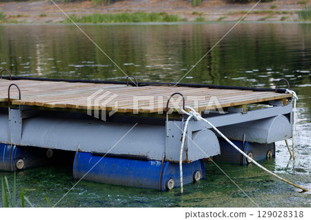 A Tranquil View of a Floating Dock on Calm Waters Surrounded by Lush Greenery in a Peaceful Natural Environment Ideal for Reflection and Leisure Activities 129028318