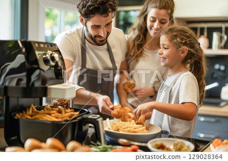 Family wearing aprons is cooking fried chicken and French fries in a modern kitchen using an air fryer Family wearing aprons is cooking fried chicken and French fries in a modern kitchen using an air fryer 129028364